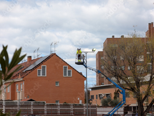 Obraz na płótnie Worker uses lift to install lights on building in residential ar w salonie