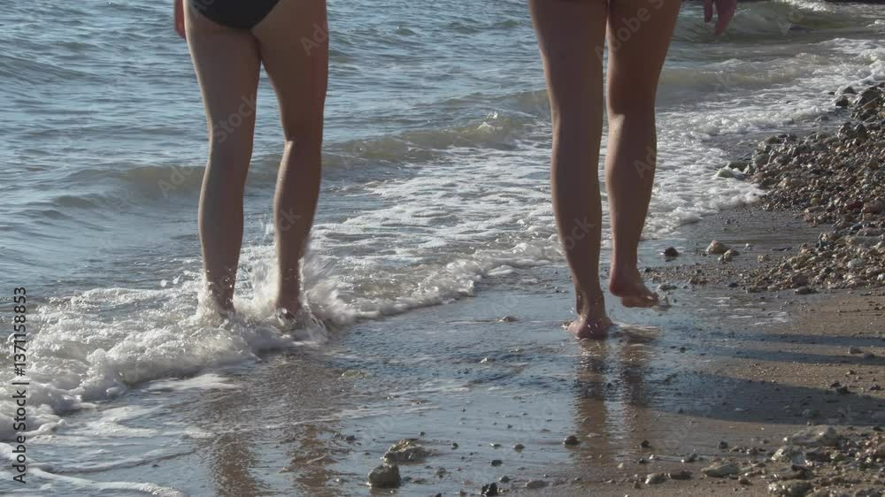 Two Women in Swimsuits Walking on the Sea Beach Shore Footage. Two Women in Swimsuits Walking on the Sea Beach Shore Footage.