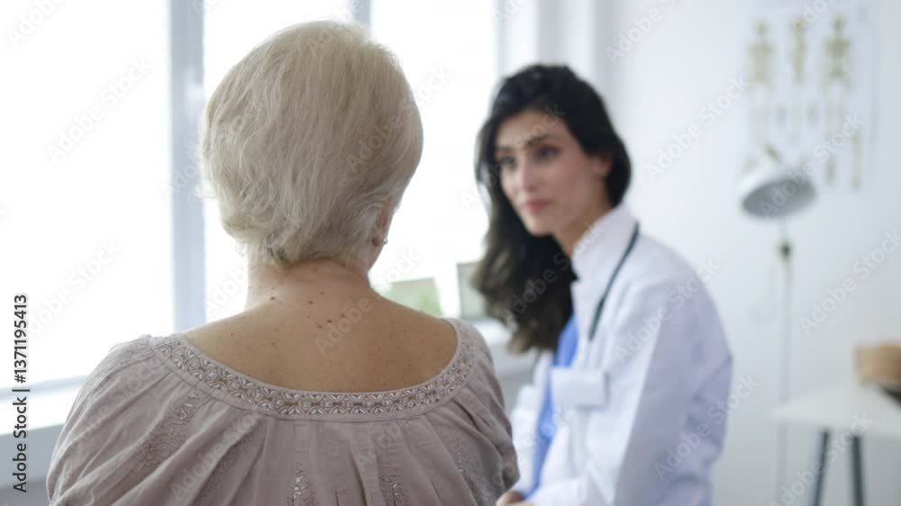 Friendly Doctor Consults with Elderly Female Patient in Medical Office Friendly Doctor Consults with Elderly Female Patient in Medical Office