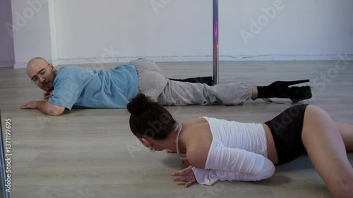 A young woman shows booty movements by teaching a stern man seductive dancing