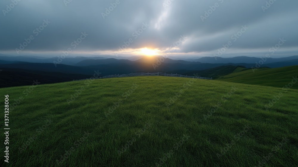 Obraz premium Lush green meadow atop a mountain range at sunset. Dramatic clouds and sunlight break through the stormy sky