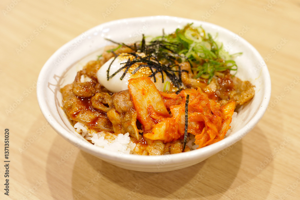 Delicious rice bowl topped with grilled pork, kimchi, a soft-boiled egg, sliced green onions, shredded seaweed, and sesame seeds, served with a flavorful sauce Delicious rice bowl topped with grilled pork, kimchi, a soft-boiled egg, sliced green onions, shredded seaweed, and sesame seeds, served with a flavorful sauce