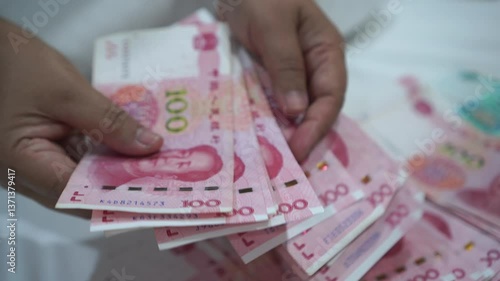 China's economy, Renminbi in global finance or world trade. Counting yuan banknotes Chinese currency (Renminbi or RMB) featuring 100-yuan banknote with Mao Zedong's portrait