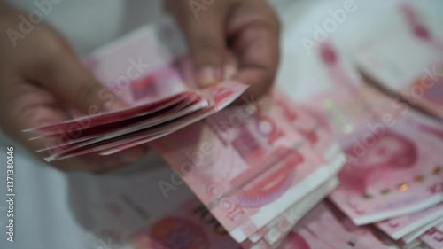 China's economy, Renminbi in global finance or world trade. Counting yuan banknotes Chinese currency (Renminbi or RMB) featuring 100-yuan banknote with Mao Zedong's portrait