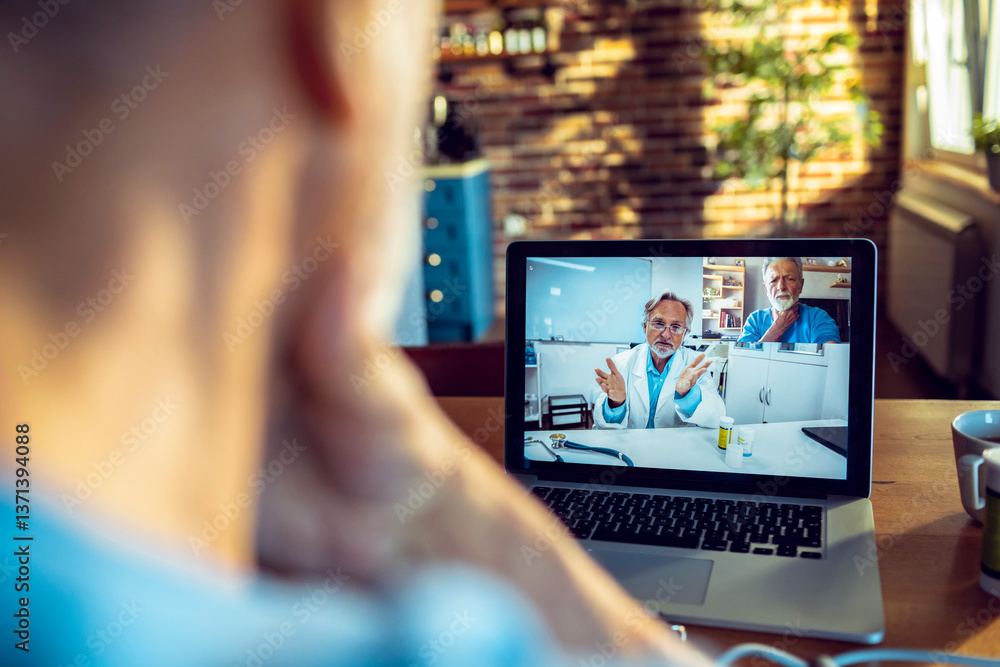 Fototapeta premium Senior man having a video call with his doctor on the laptop while having breakfast in the morning