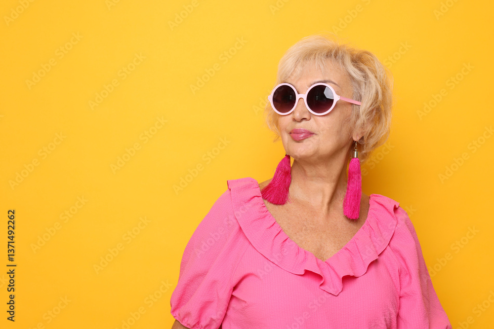 Fototapeta premium Portrait of fashionable grandmother in sunglasses on orange background. Space for text
