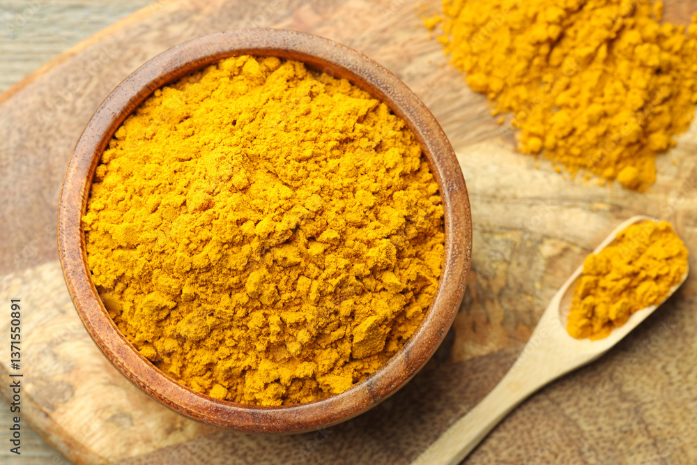 Turmeric powder in bowl and spoon on table, top view Turmeric powder in bowl and spoon on table, top view