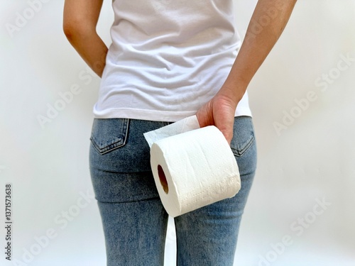 Back view of a woman holding toilet paper next to her hip, portraying a subtle reference to discomfort or urgency. Appropriate for stomach-related or hygiene content.