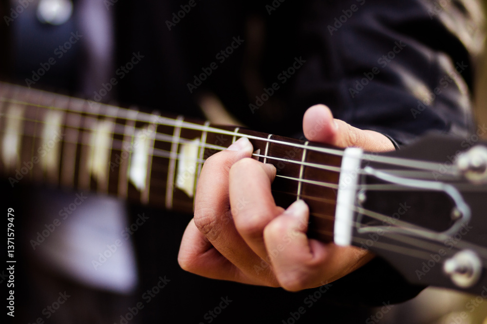 Young person fingering strings on guitar Young person fingering strings on guitar