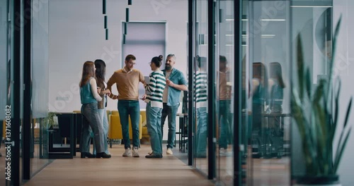 Business team in a modern open space startup office walking together. Diverse group of businesspeople smiling while having a discussion. Successful mixed race colleagues collaborating on a new project