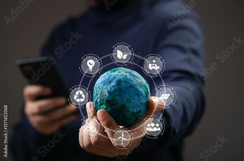 A person holding a model globe with digital icons representing environmental sustainability, technology, and mobile connectivity, symbolizing eco-consciousness.