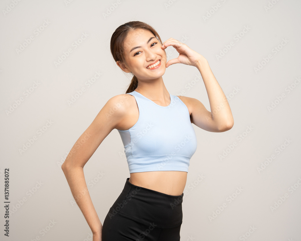 Young beautiful smiling asian woman with sportswear showing mini heart on isolated white background. Portrait happy healthy slim fit and firm latin attractive sporty woman heart sign pose Young beautiful smiling asian woman with sportswear showing mini heart on isolated white background. Portrait happy healthy slim fit and firm latin attractive sporty woman heart sign pose