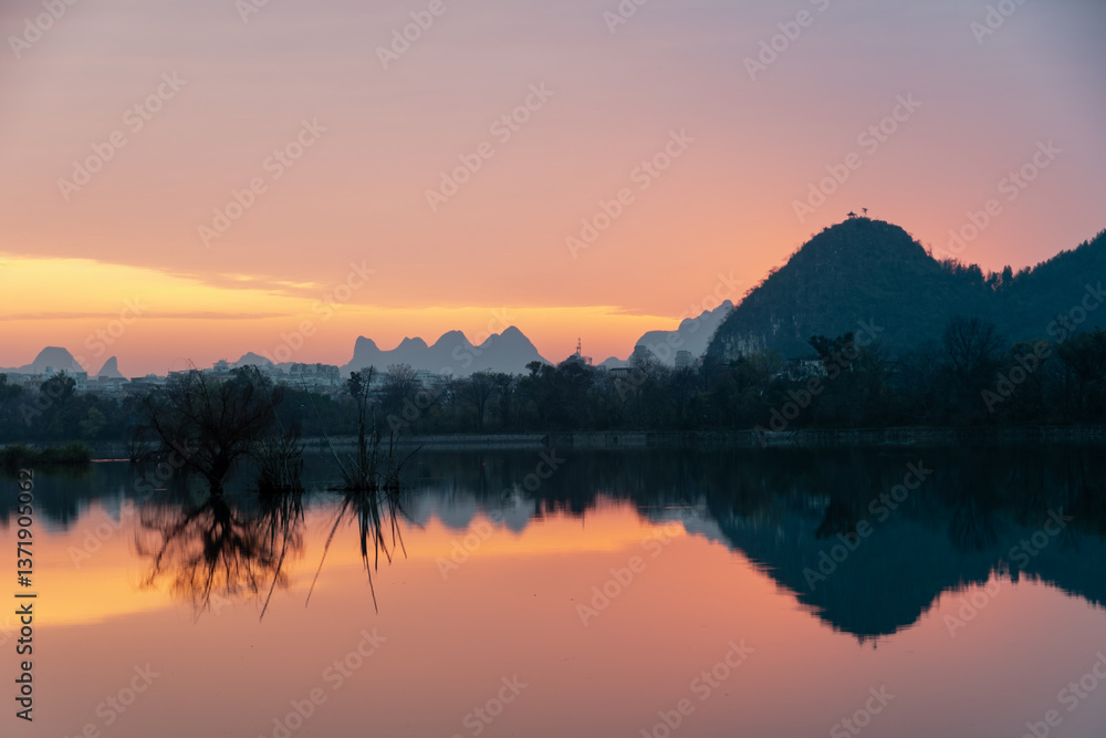 Fototapeta premium Golden Dawn on Li River: Misty Karst Peaks Reflecting in Mirror-Still Waters – Guilin's Ethereal Morning Symphony