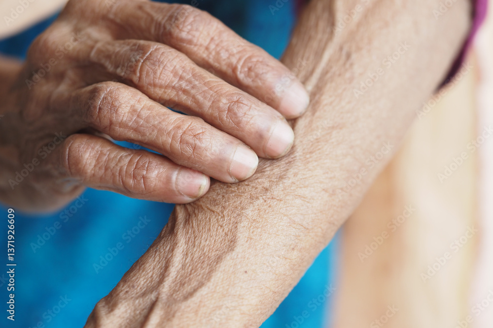 Fototapeta premium Close-up of an elderly hand resting on the arm in natural light