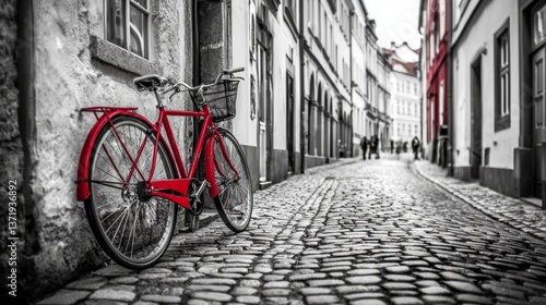 Retro vintage red bike on cobblestone street in the old town. Color in black and white. Old charming bicycle concept.