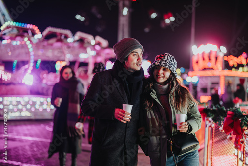 Фотография Friends spend time together at a nighttime holiday fair, enjoying the festive atmosphere with bright lights and cheerful vibes