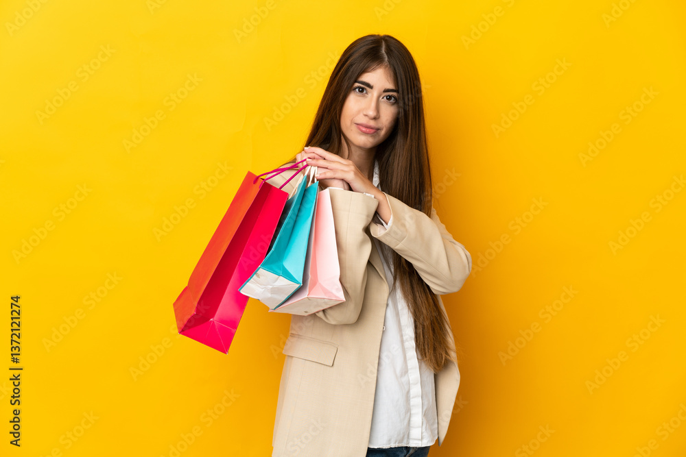 Young caucasian woman isolated on yellow background holding shopping bags Young caucasian woman isolated on yellow background holding shopping bags