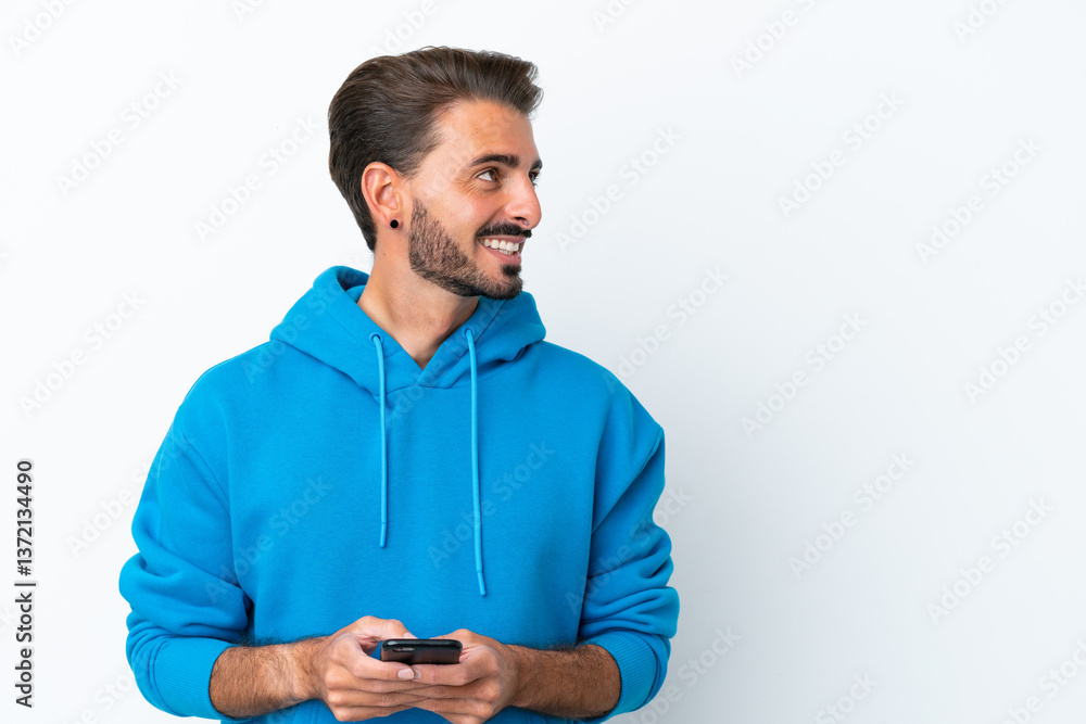 Young caucasian man isolated on white background using mobile phone and looking up Young caucasian man isolated on white background using mobile phone and looking up