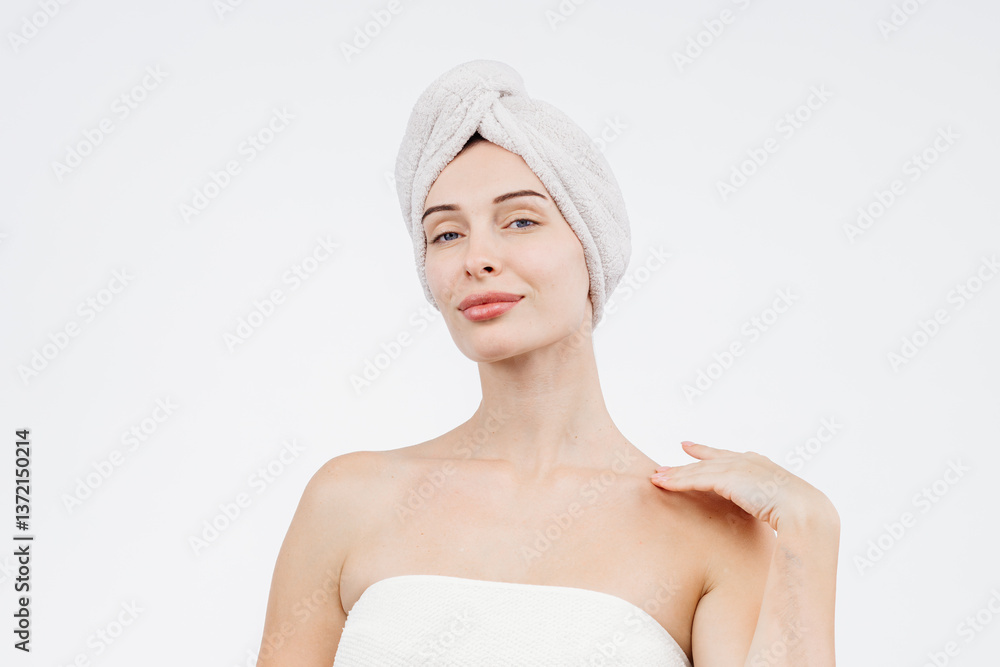 Woman on white background with bath towel on her head holding skin care product. Concept of cosmetology and skin and hair care. Woman on white background with bath towel on her head holding skin care product. Concept of cosmetology and skin and hair care.
