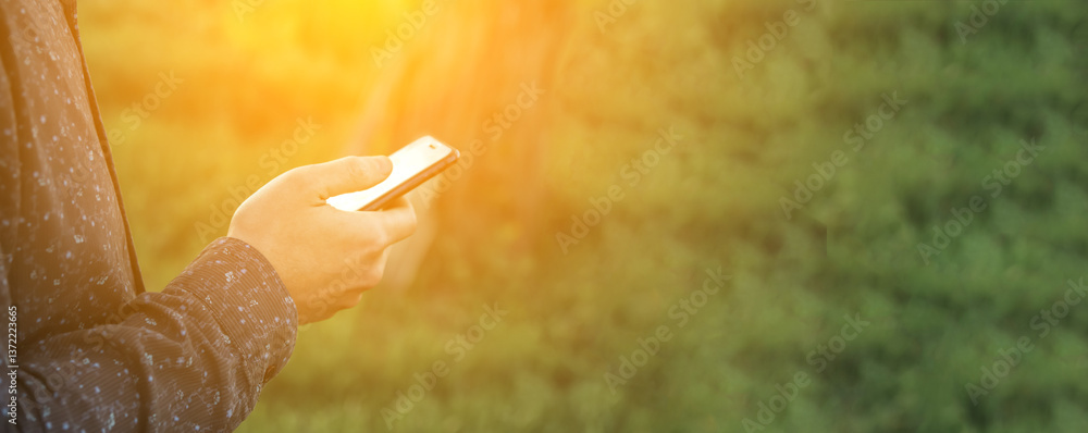 A man holding a smartphone with a green-themed interface, illuminated by a soft lens flare. The blank copy space makes it ideal for advertisements, app promotions, or messaging concepts