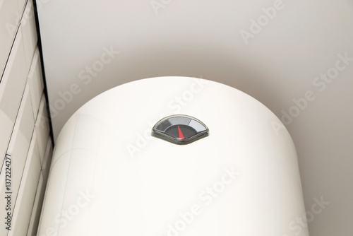 Obraz na płótnie A white boiler hanging on a wall in a bright home interior, representing modern water heating technology and home efficiency w salonie