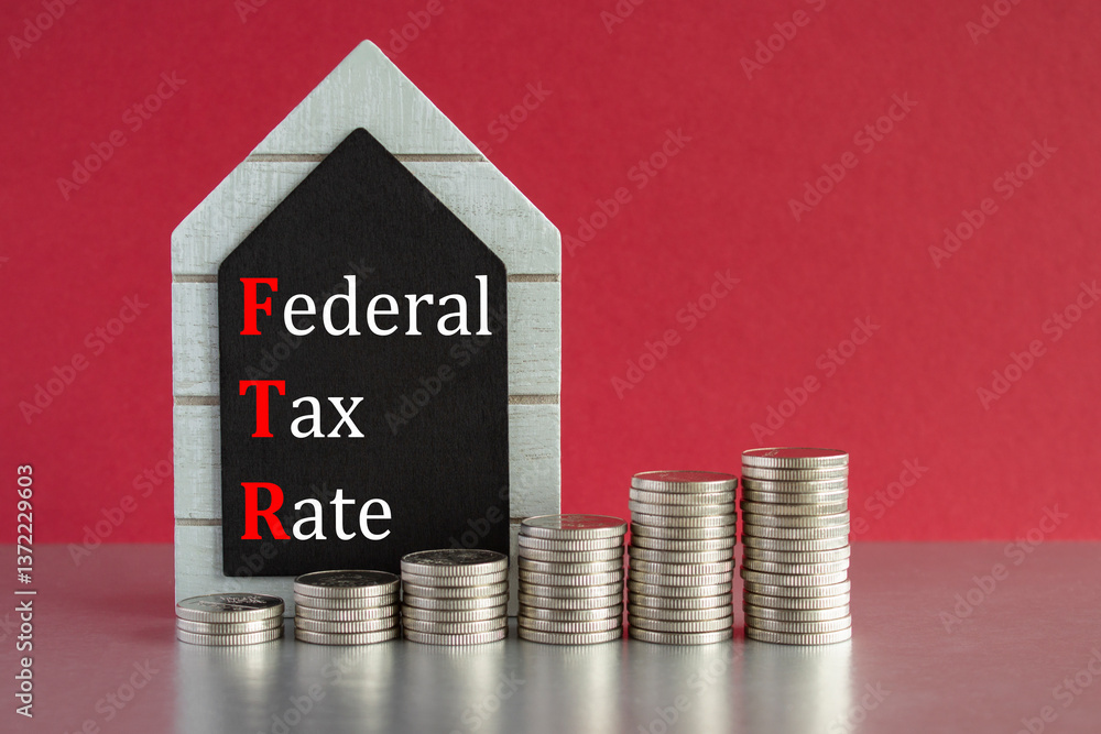Federal tax rates symbol. Concept words Federal tax rates written on a black board. Silver coins arranged in a graph in front. Beautiful red background, grey table. Business concept.
