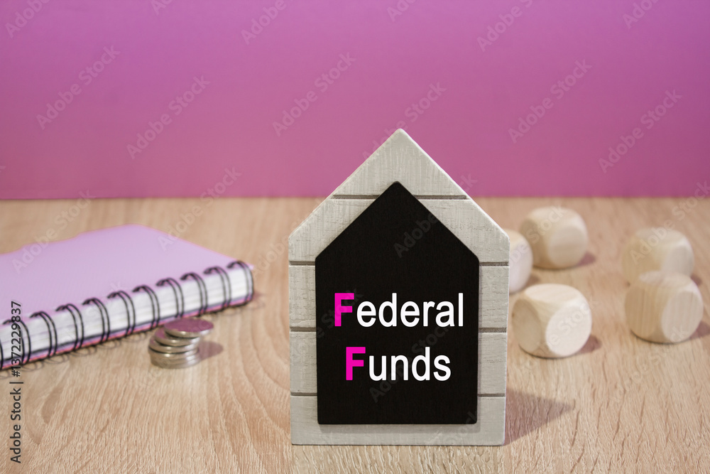 Text FEDERAL FUNDS on a black board. Beautiful purple background. Notebook and silver coins on the table. Business concept.