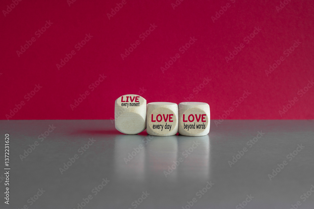 The expression 'live every moment, love everyday, love beyond words' on wooden cubes. Beautiful red background. Inspirational quote