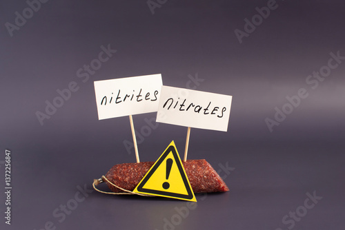 Foto A fragment of smoked sausage and warning labels nitrates and nitrites in close-u