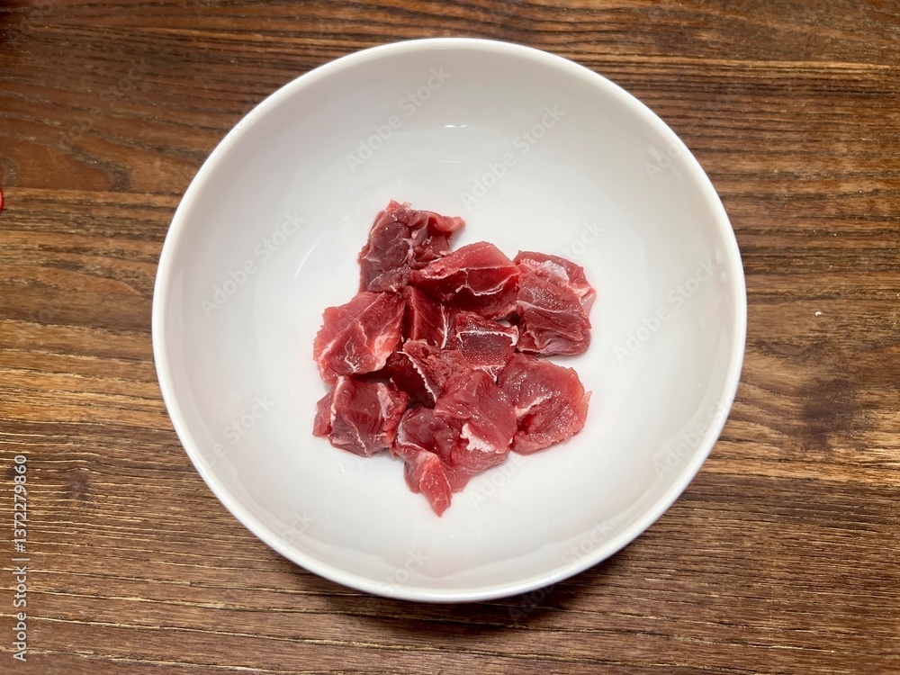 Fresh raw premium beef shank, ingredients for making dishes. Placed in a white ceramic bowl, on a wooden table. Fresh raw premium beef shank, ingredients for making dishes. Placed in a white ceramic bowl, on a wooden table.