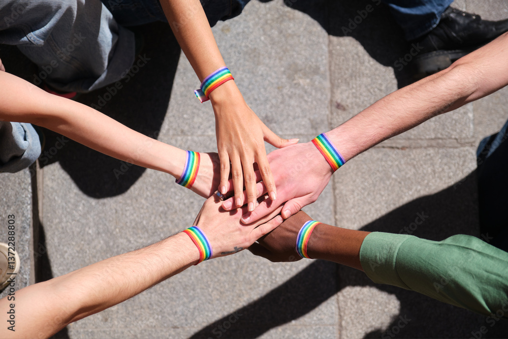 Group of activists joining hands wearing rainbow wristbands at a LGBT pride parade celebrating diversity and inclusion