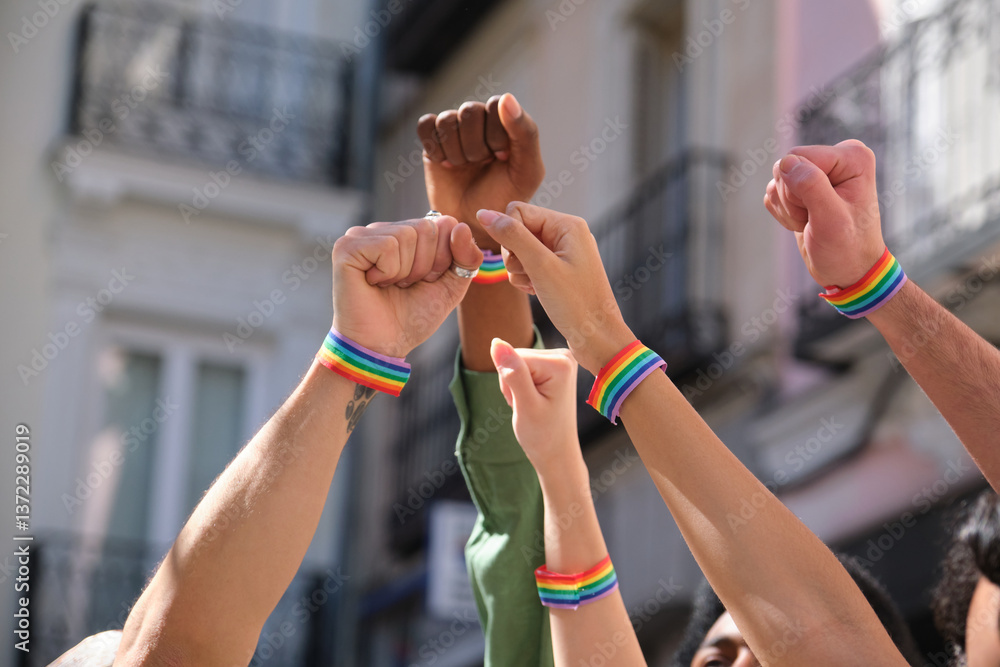 Activists are raising fists wearing rainbow bracelets at a LGBT pride parade