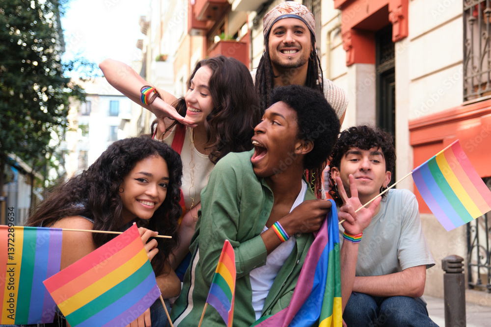 Group of happy multi ethnic friends having fun together at a LGBT pride parade, waving rainbow flags and wearing rainbow bracelets