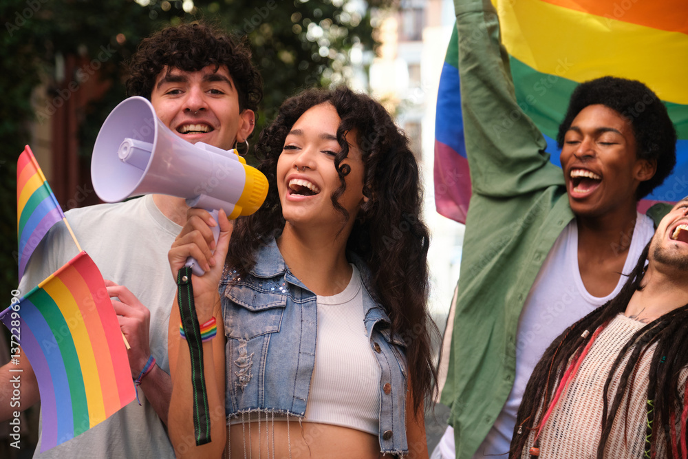 Group of young activists holding rainbow flags and shouting with megaphone at a lgbt pride parade