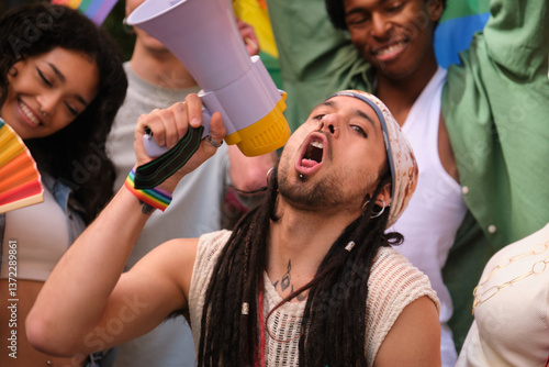 Obraz na płótnie Young man speaking with megaphone during lgbt pride parade, surrounded by friends w salonie