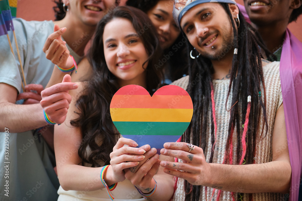 Group of smiling multi ethnic young people holding rainbow heart celebrating LGBT pride