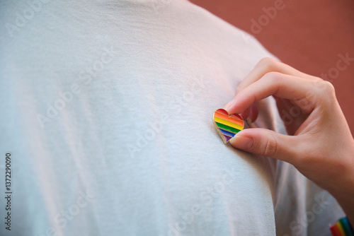 Obraz na płótnie Close up of hand pinning rainbow heart to white t shirt, symbolizing support and celebration of LGBT pride w salonie