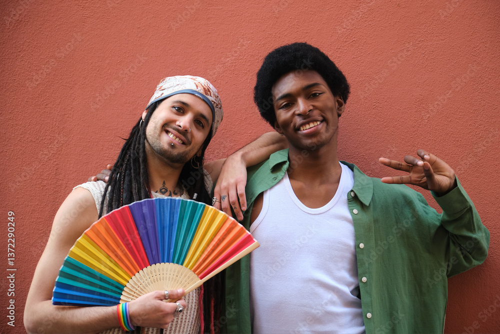 Two male friends embracing and showing their support for LGBT community with a rainbow fan