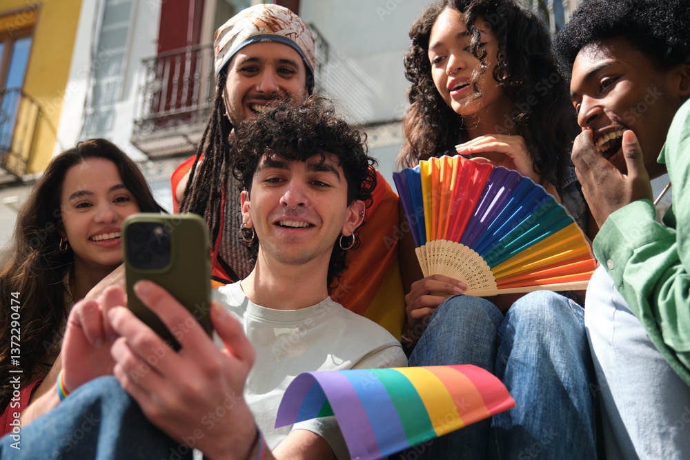 Young people celebrating gay pride holding rainbow flag and fan, looking at smartphone