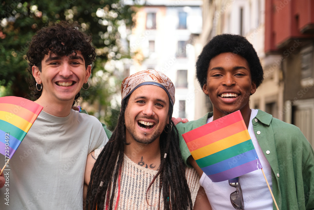 Three happy multi ethnic friends are celebrating gay pride holding rainbow flags