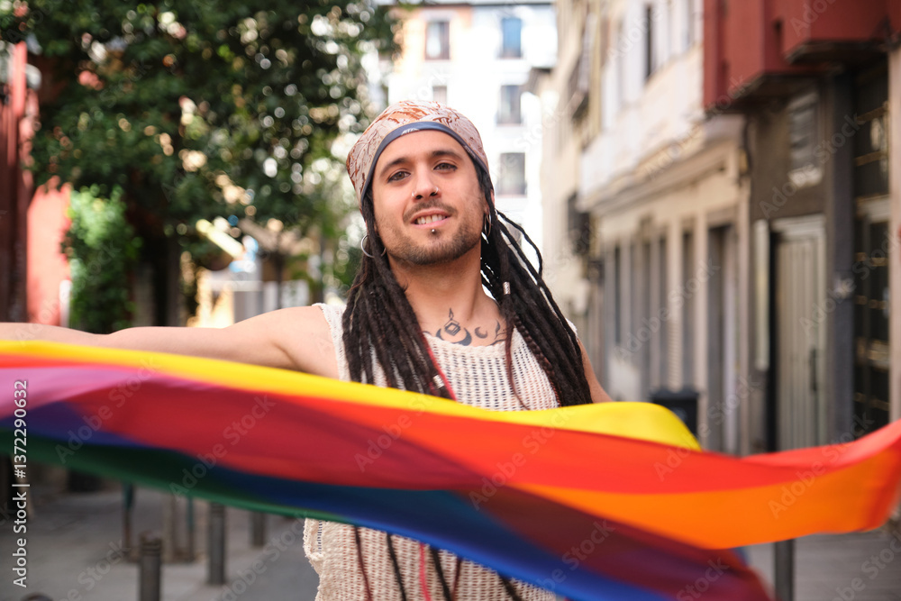 Young artist with dreadlocks holding rainbow flag celebrating LGBT pride in the city
