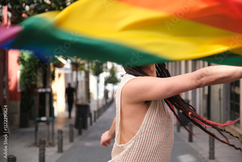 Obraz na płótnie Young man with dreadlocks waving rainbow flag celebrating LGBT pride in the street w salonie