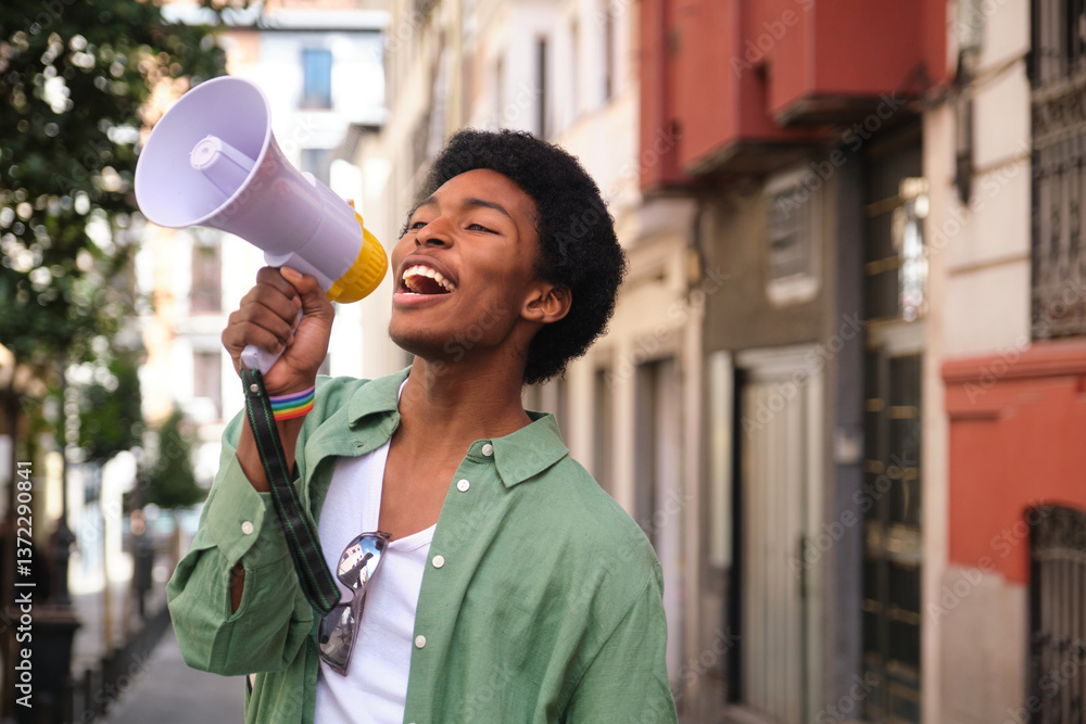 Young man with LGBT wristband using megaphone to make his voice heard during a pride parade