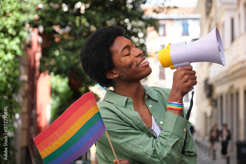 Obraz na płótnie Young activist holding rainbow flag and speaking into megaphone during LGBT pride parade w salonie