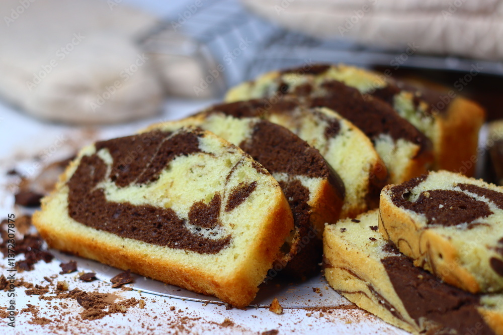 Slices of moist marble cake with chocolate and vanilla swirls, placed on a white surface. Slices of moist marble cake with chocolate and vanilla swirls, placed on a white surface.