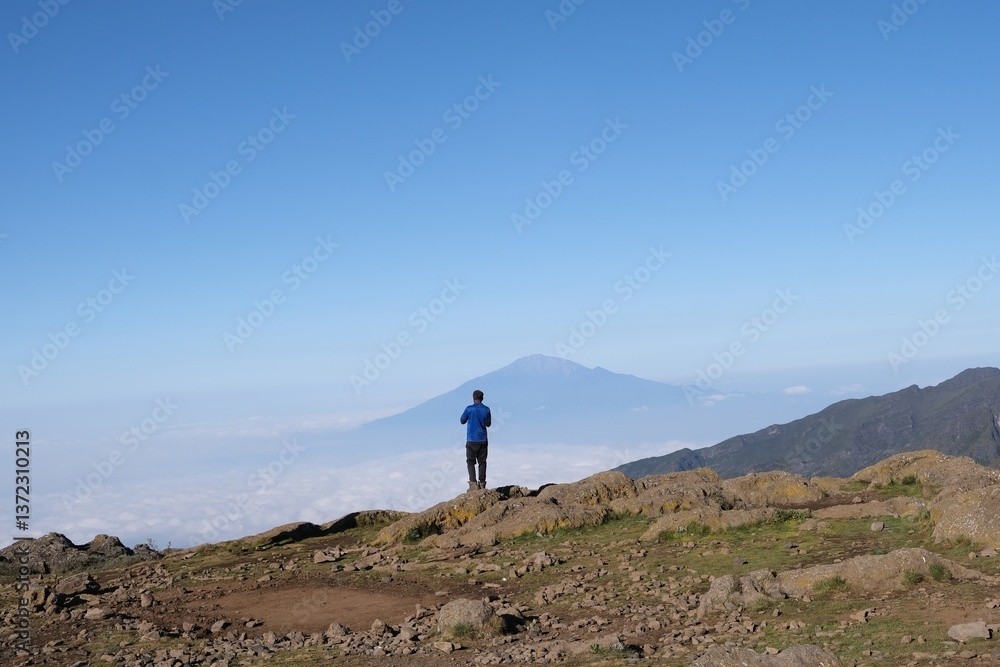 Kilimanjaro, Tanzania: Single man standing on viewpoint on Shira Camp with Mount Meru in background. Machame Route,