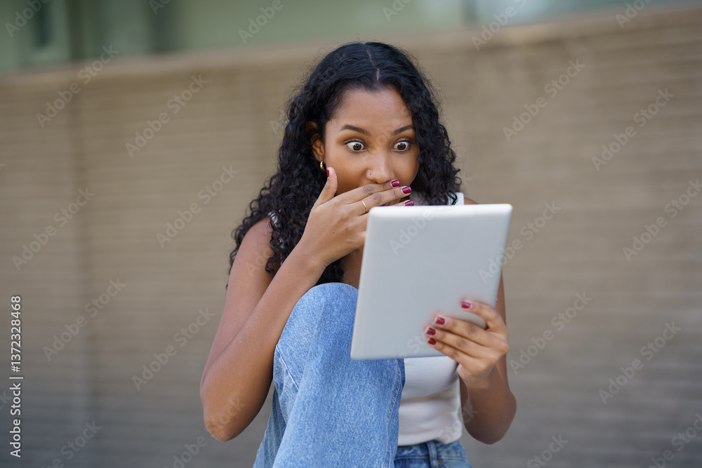 Fototapeta premium A surprised woman enjoys content on her tablet in a relaxed setting, engaging with joy