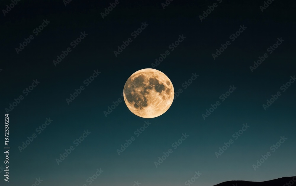 Obraz premium Large Yellow-Gold Full Moon in Dark Teal Night Sky over Silhouetted Mountains