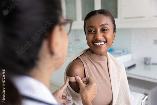 Canvas Print Cheerful young African patient woman visiting doctor for vaccination, talking to
