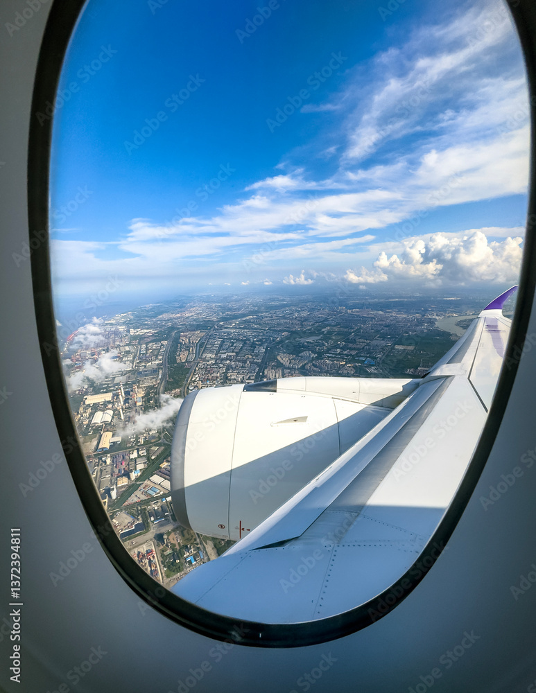 View from an airplane window showcasing a cityscape under a clear blue sky View from an airplane window showcasing a cityscape under a clear blue sky